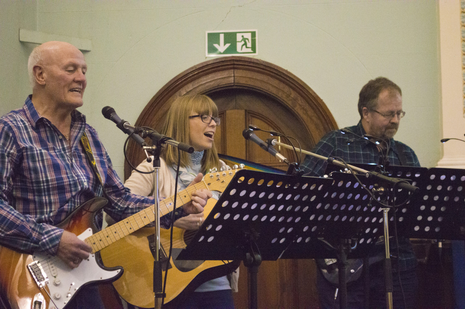 Three musicians playing guitar and singing in church