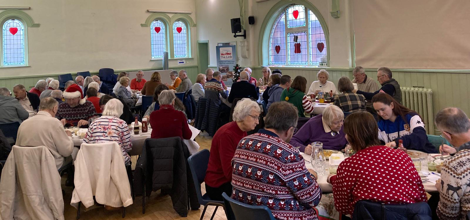 A photo of a church hall full of people, some wearing Christmas jumpers