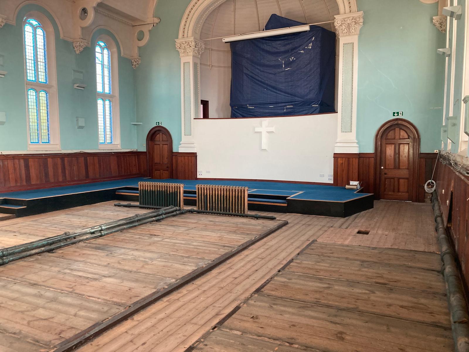 The interior of the main worship space at Ashbourne Methodist Church, with all pews removed ready for the building's transformation. The photo also shows the organ wrapped to protect it during the works.