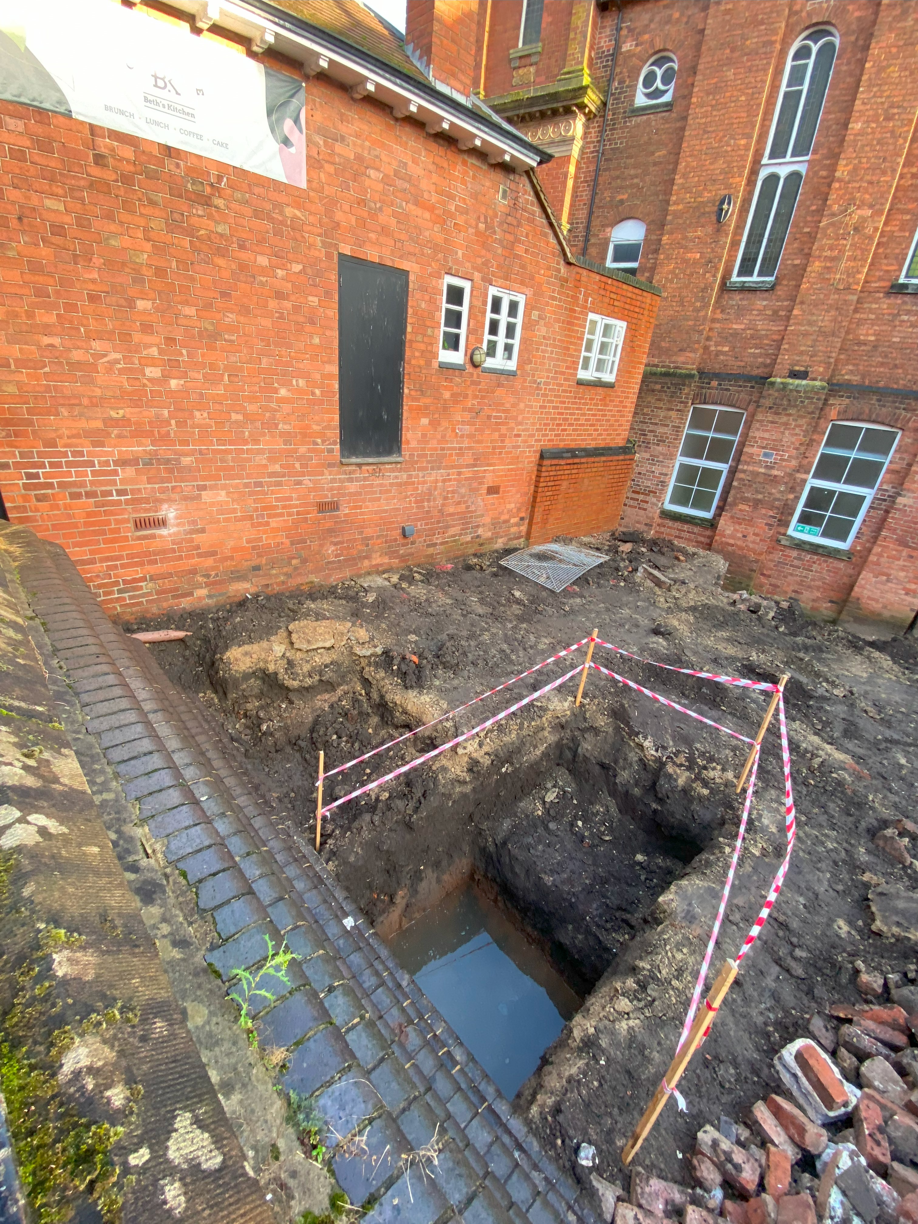 A pit has been dug down to lower floor level, examining ground conditions, with the waste material used to make access for construction equipment. This is the area where the new Link Centre foyer and meeting rooms will be located.