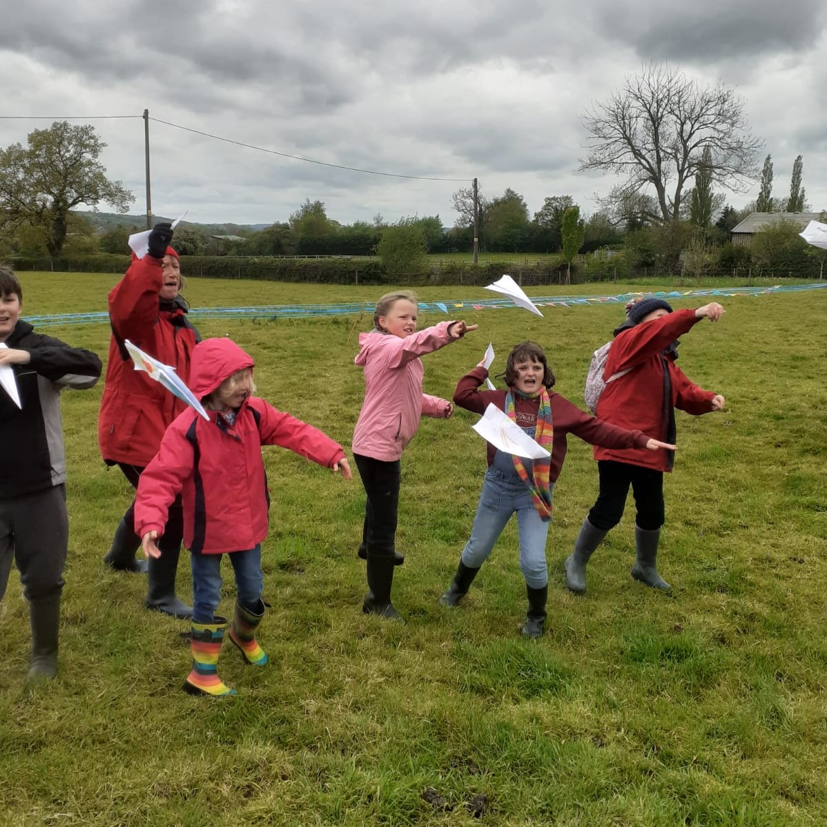 Photo of children in a field throwing paper planes